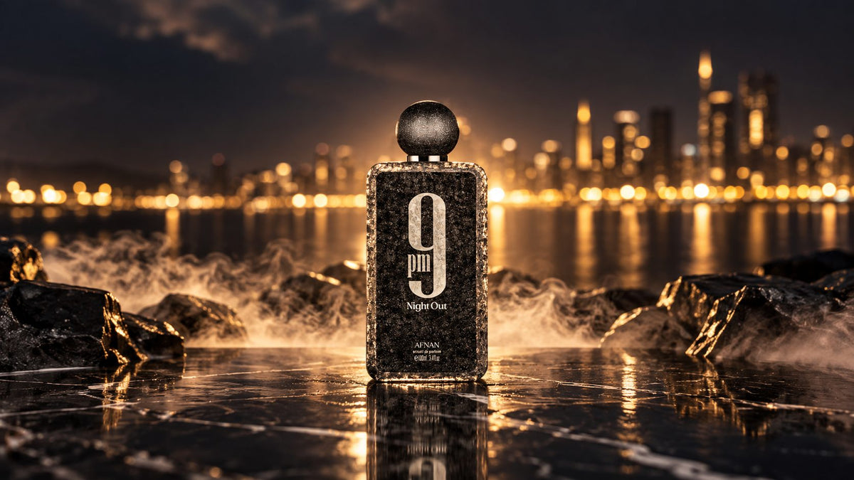 Flacon 9PM Night Out d’Afnan, extrait de parfum, posé sur des rochers noirs devant une ville illuminée de nuit