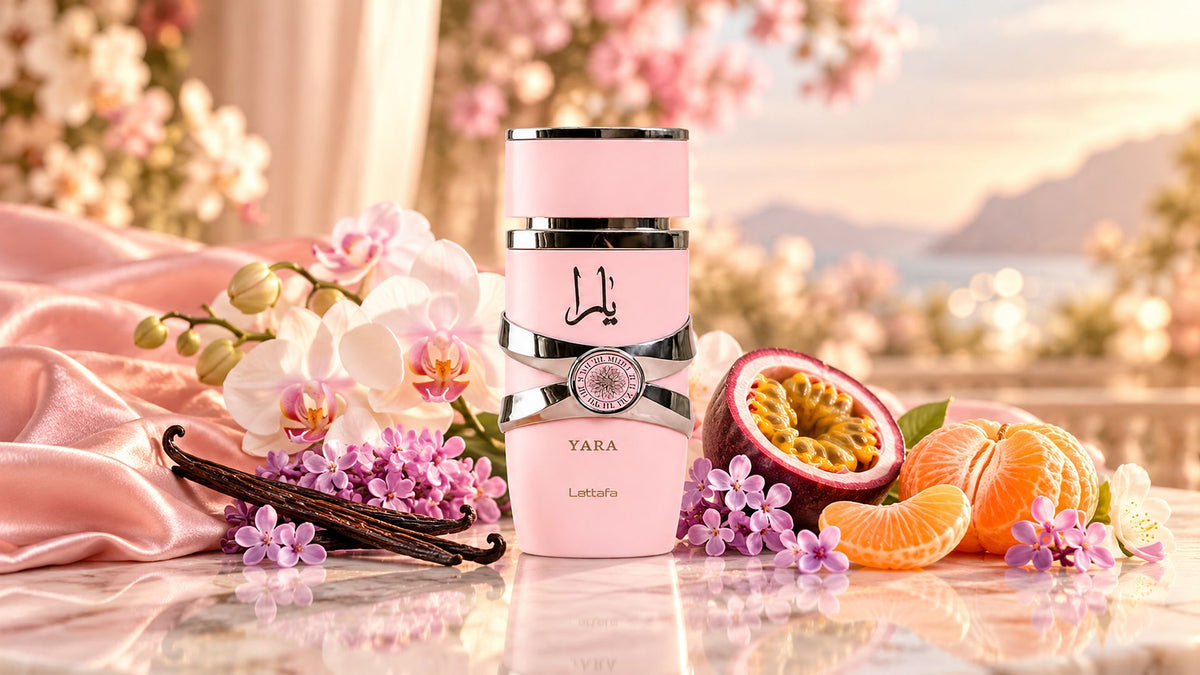 Flacon rose Yara de Lattafa entouré de gousses de vanille, orchidées blanches, fleurs lilas, fruit de la passion et mandarine sur du marbre crème